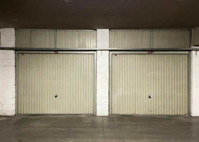 Two closed garage doors inside an empty warehouse space.