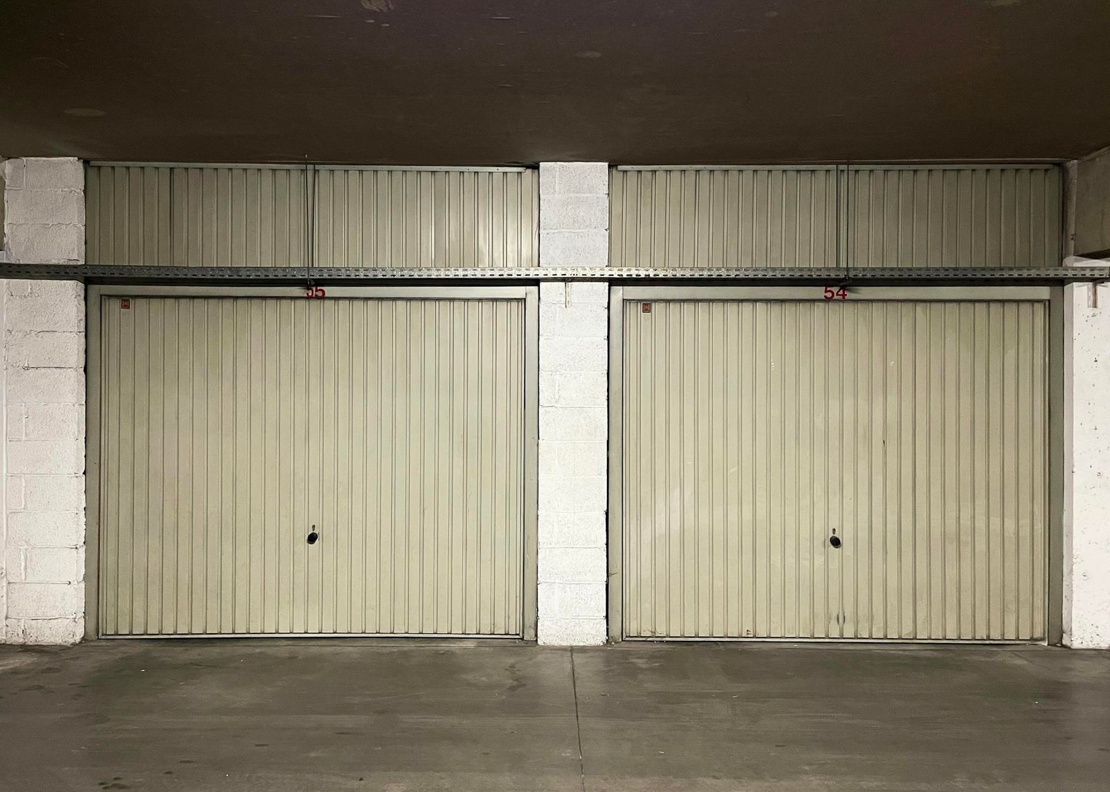 Two closed garage doors inside an empty warehouse space.